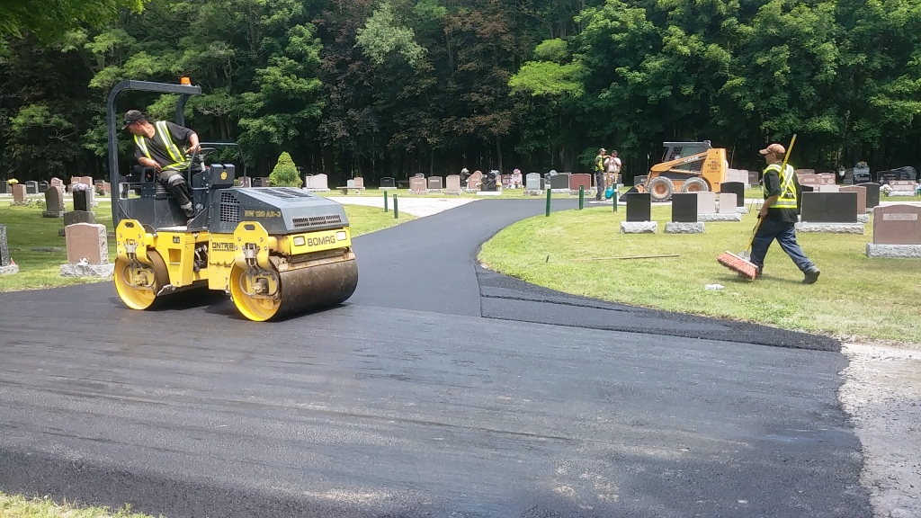 Construction crew using roller to finish paving new road